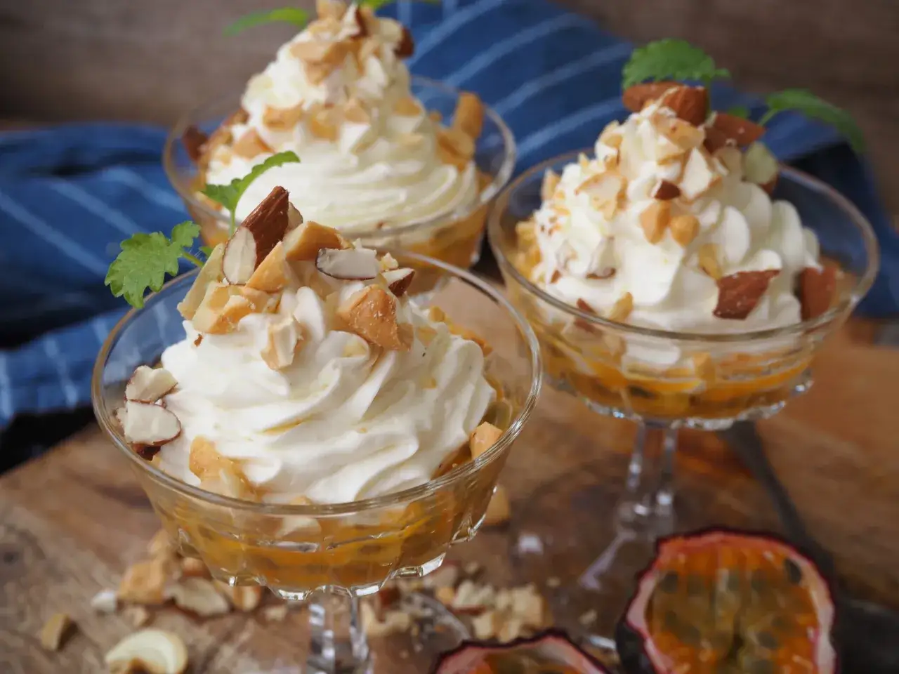 Tre eleganta glas med krämig mascarpone dessert, toppad med mandel och mynta. Passionsfrukt i botten ger en tropisk touch.