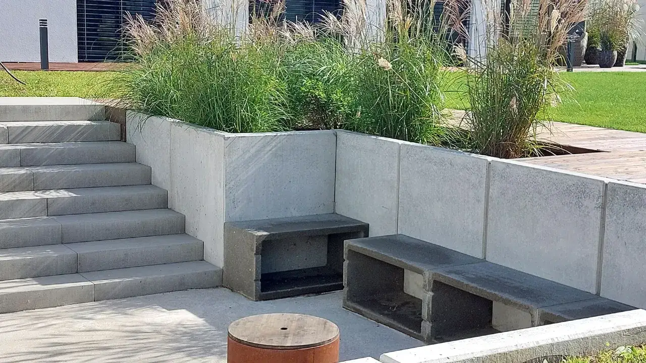 Nowoczesny ogród z betonowym murem, schodami i siedziskami. Zastanawiasz się, czym obłożyć murek betonowy? Tutaj beton stanowi główny materiał.