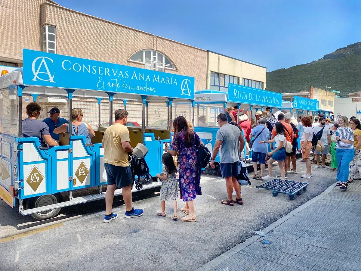 Gente disfrutando de la feria de la anchoa en Santoña, subiendo a un tren turístico de