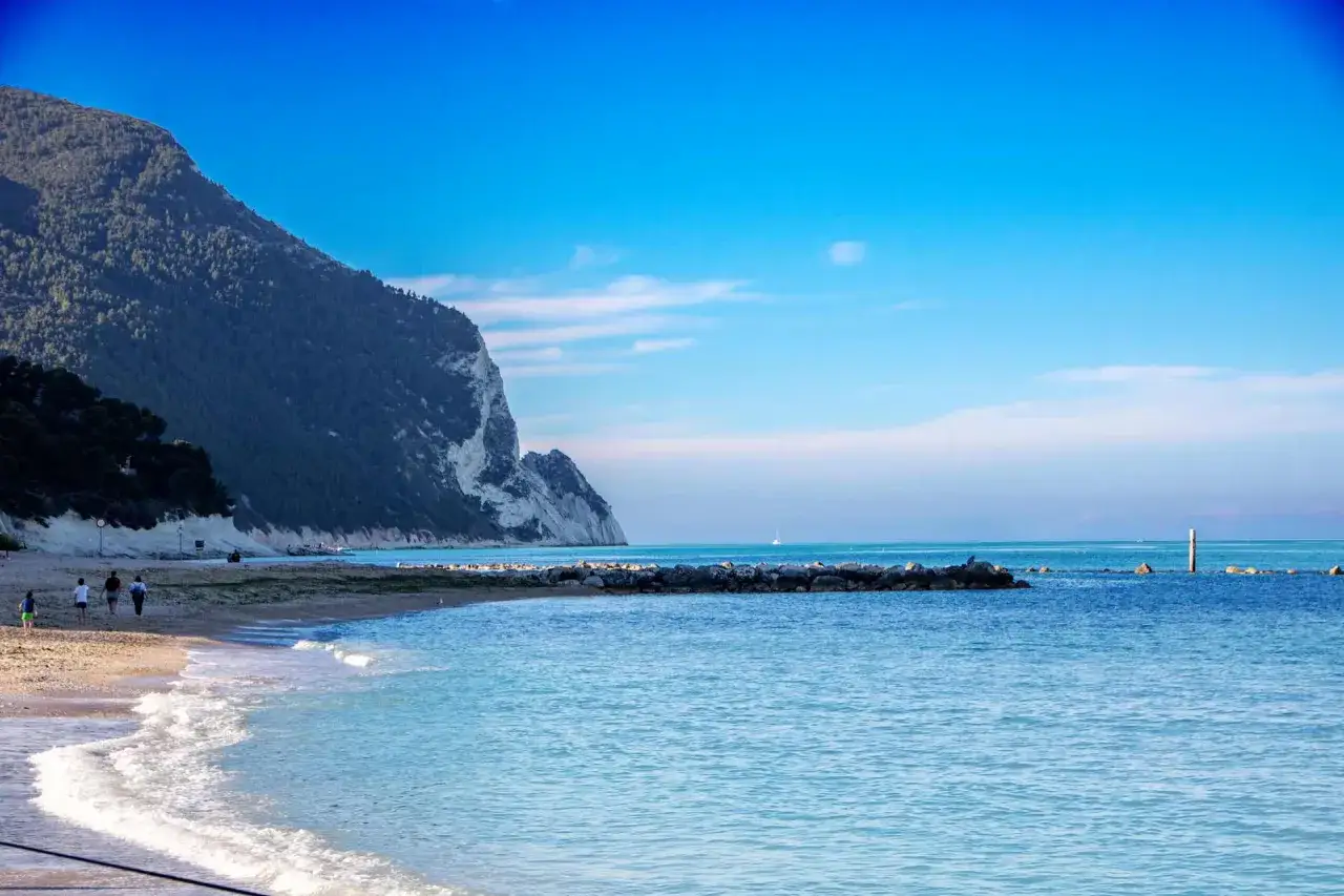 Spiaggia con scogliera e mare azzurro, ideale per scoprire le località balneari Marche economiche.