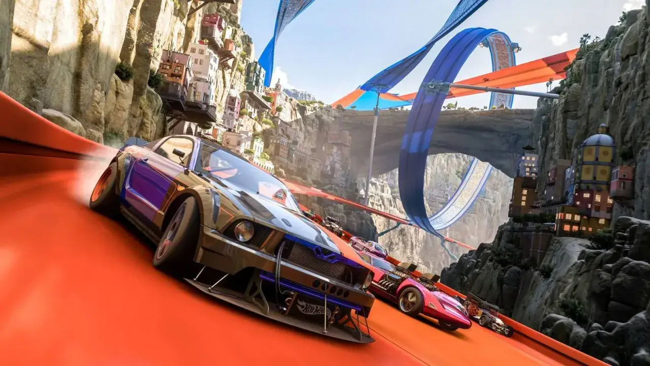 Wyścigowe samochody pędzą po pomarańczowym torze Hot Wheels, a ich załoga przygotowuje się na ekstremalne zjazdy i pętle wśród górskich zabudowań.