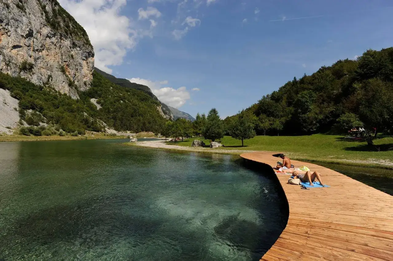 Relaxing sul pontile in un lago alpino, con montagne maestose che ricordano l'Adamello Brenta.