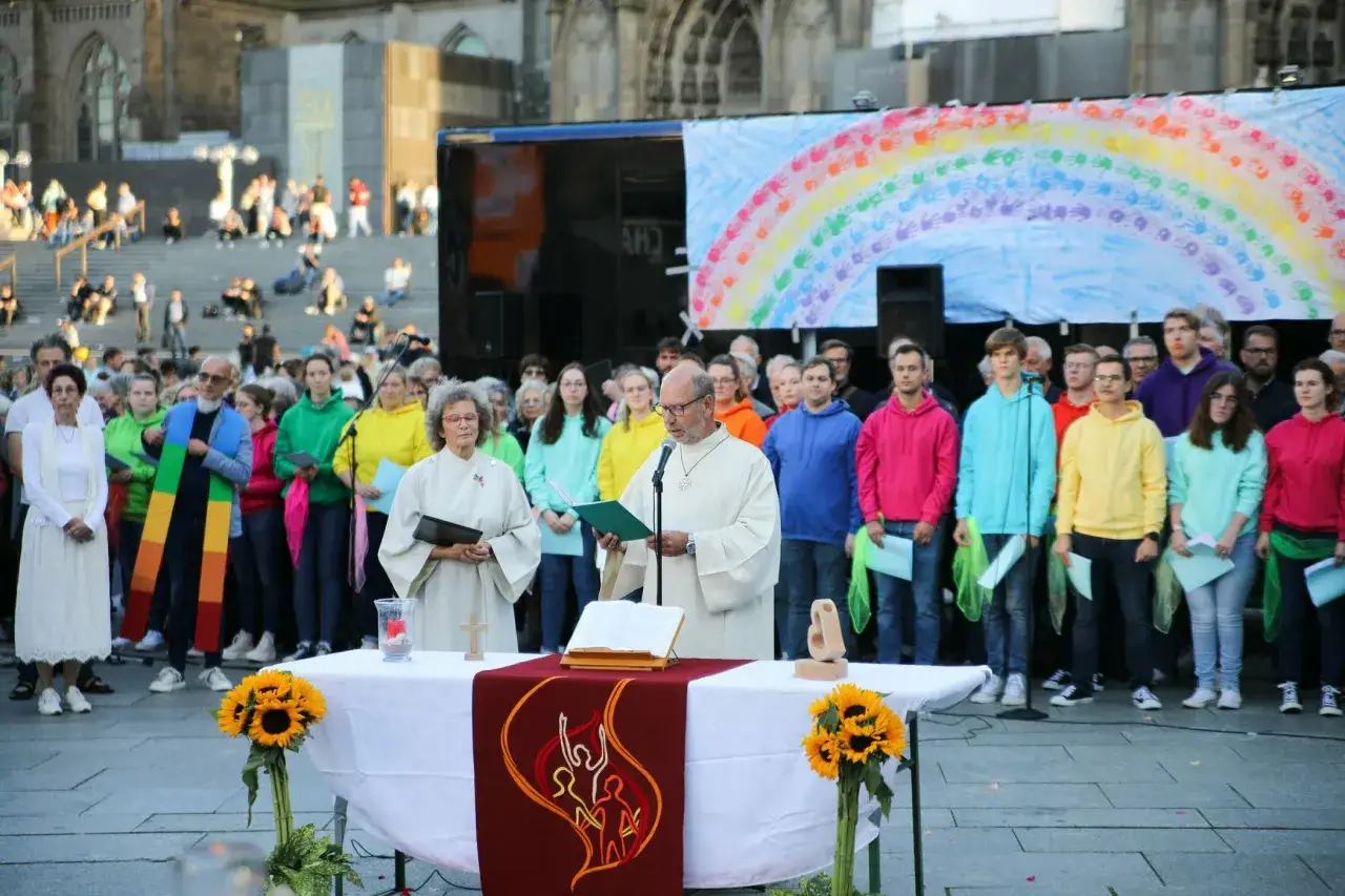 Gottesdienst mit Regenbogenbanner und Menschen in bunten Hoodies. Ein Zeichen f&uuml;r die gleichgeschlechtliche Ehe in der Kirche.