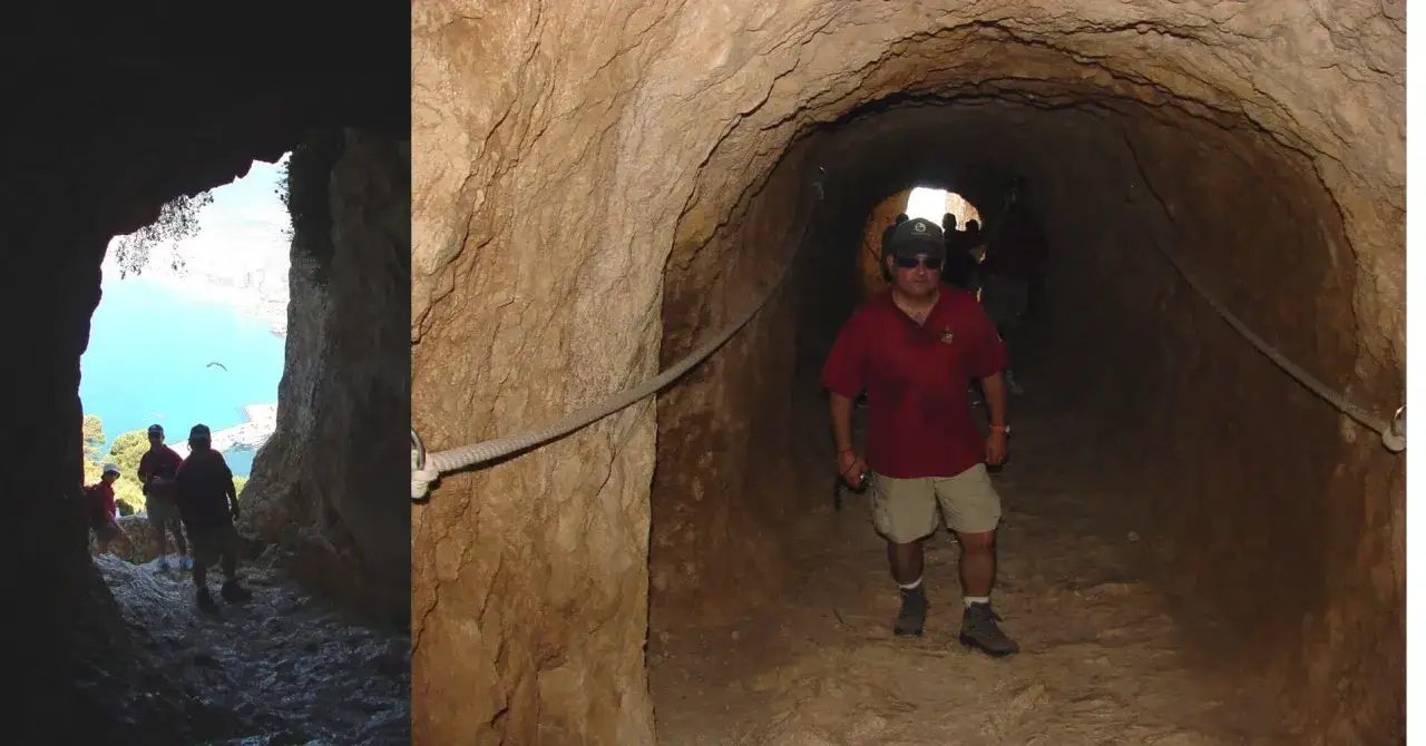Hombres caminan por un túnel en la ruta peñón de Ifach. El túnel tiene una cuerda de apoyo y la salida muestra el mar azul.