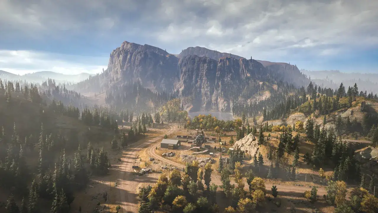Krajobraz z gry Far Cry 7: rozległe góry, lasy i baza z wieżą obserwacyjną.