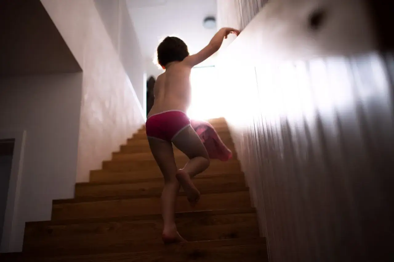 Ni&ntilde;o subiendo escaleras en ropa interior, con una manta rosa. Podr&iacute;a ser un caso de sonambulismo ni&ntilde;os.