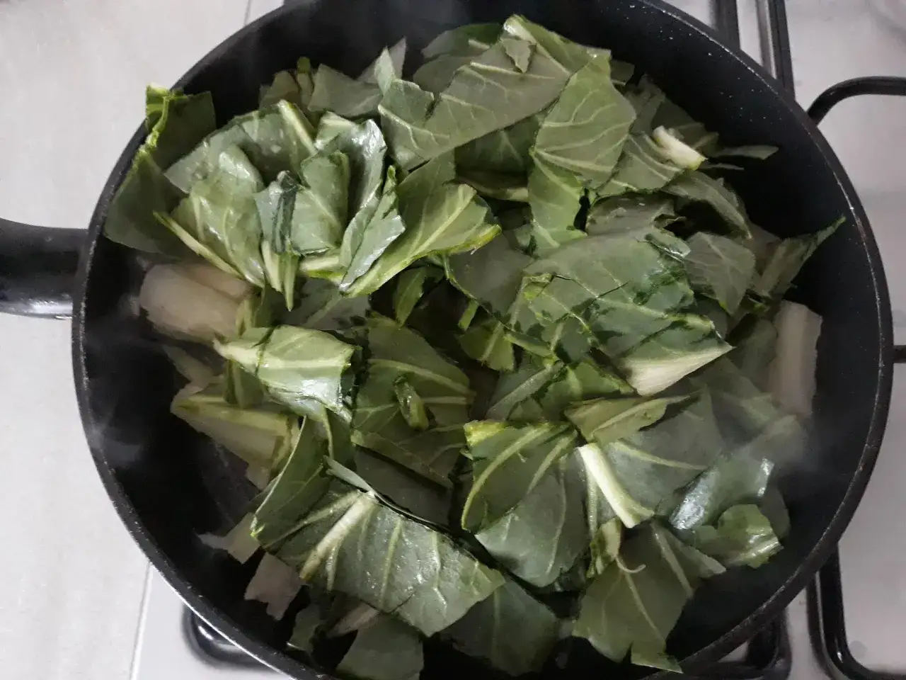 Verdure a coste in padella, che rilasciano vapore mentre cuociono.