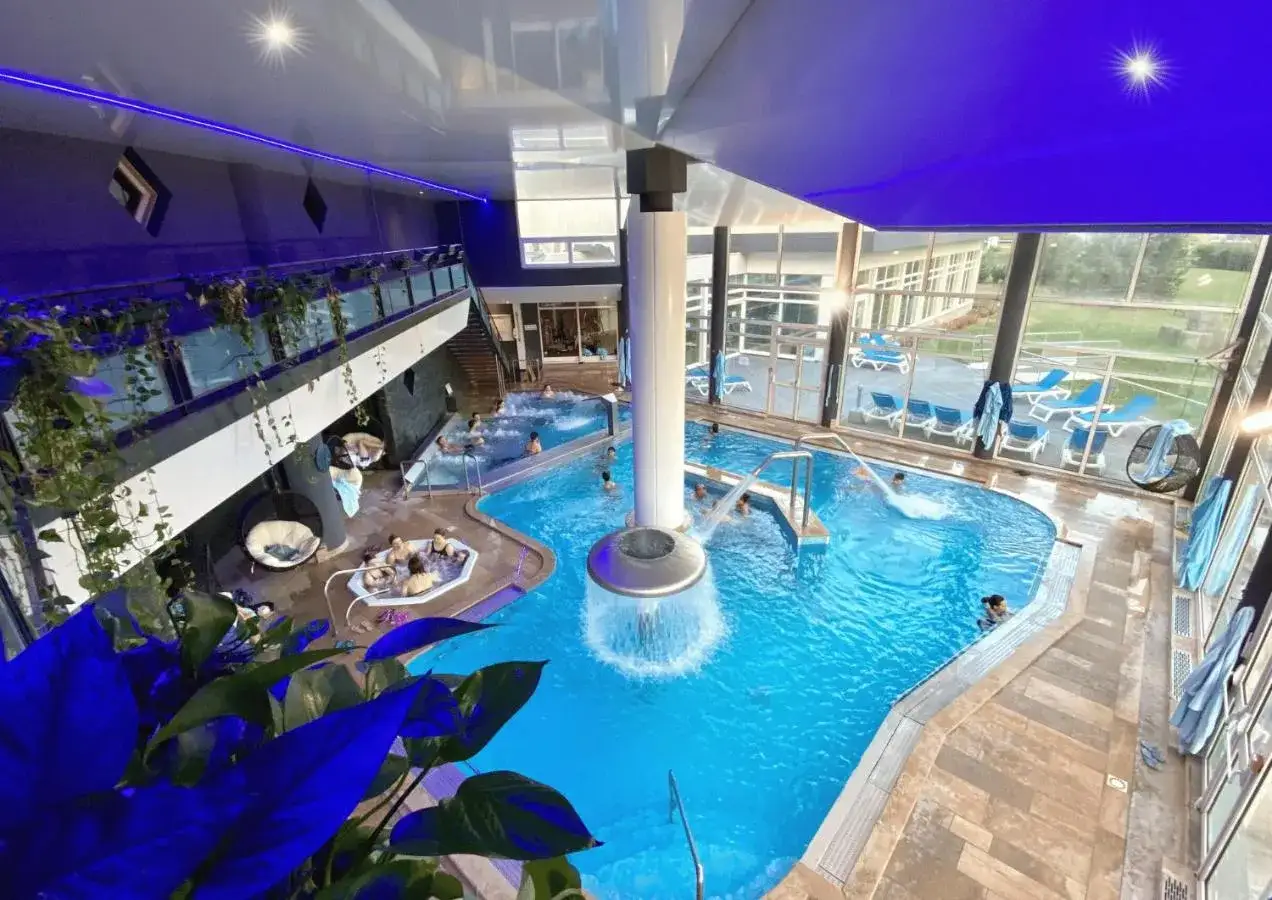 Piscine int&eacute;rieure avec cascade, jacuzzis et transats, parfait pour les activit&eacute;s &agrave; Aix-les-Bains.