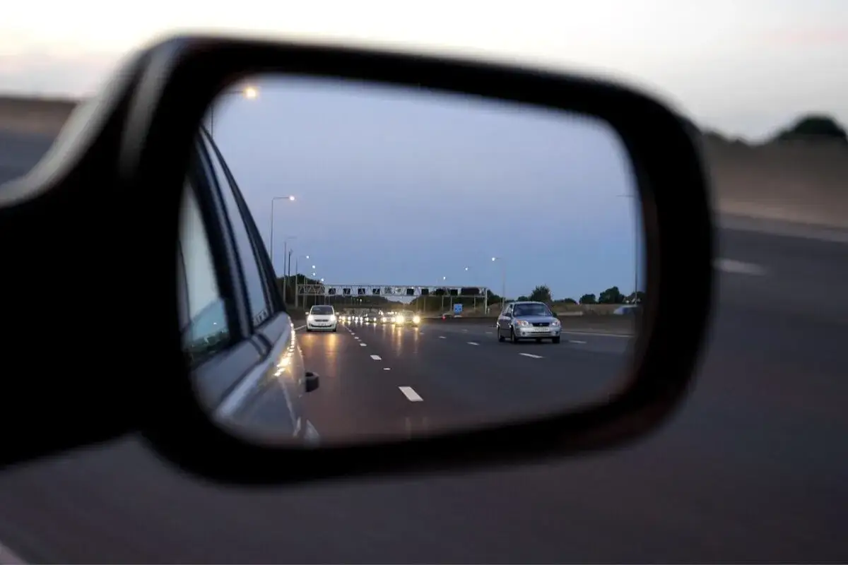 Widok z lusterka bocznego: martwe pole w samochodzie, autostrada nocą, światła innych pojazdów.