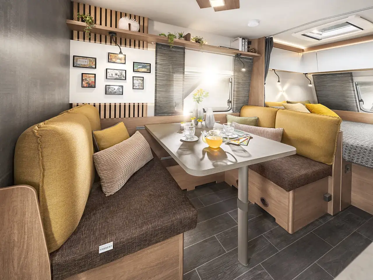 Gemütliche Sitzecke in einem Freeway Camper mit Tisch, Kissen und Blick auf das Bett.