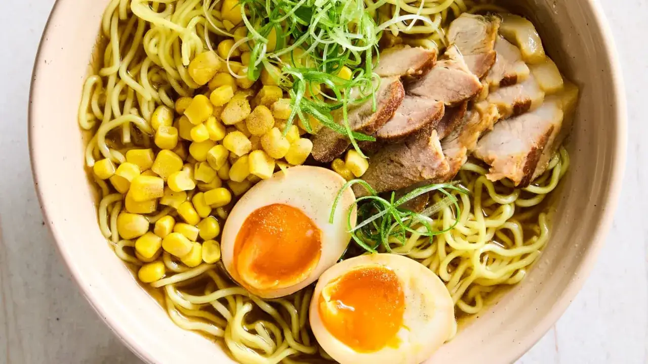 Miseczka aromatycznego shoyu ramen z makaronem, plastrami wieprzowiny, jajkiem na pół i kukurydzą.