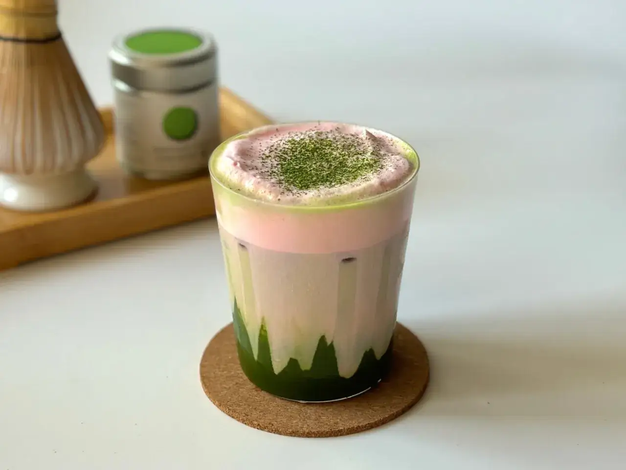 Un verre de matcha latte rose et vert, garni de poudre de matcha. Le matcha latte gout est d&eacute;licieux.