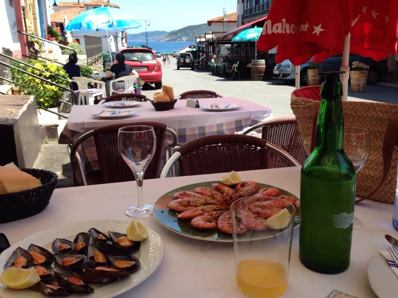 Una mesa lista para comer en tazones, con mejillones y gambas, en un día soleado junto al mar.