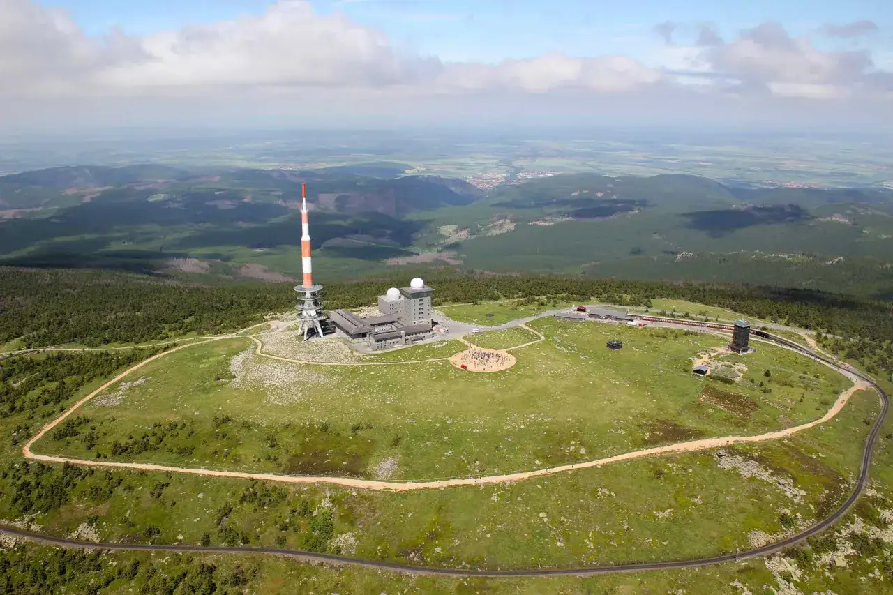 Der Brocken, in welchem Bundesland er liegt, ist ein Berg mit Funkturm und Geb&auml;uden, umgeben von W&auml;ldern und einer weiten Landschaft.