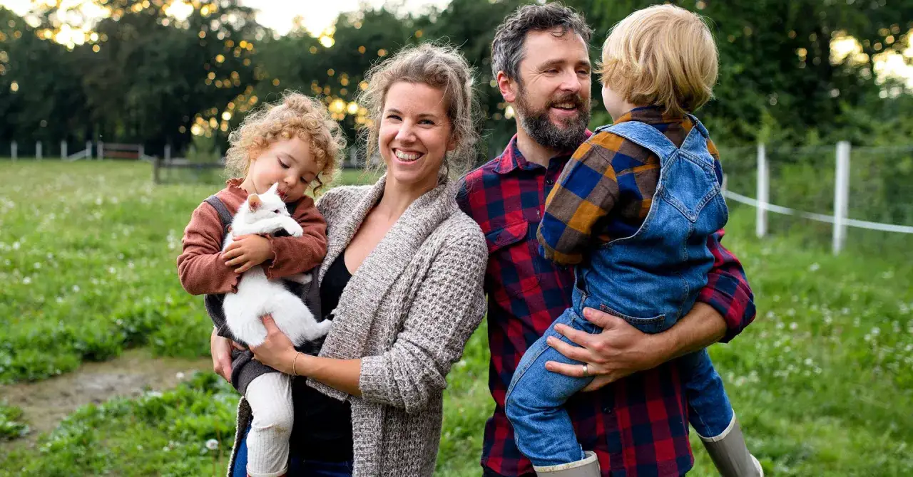 Gl&uuml;ckliche Familie mit zwei Kindern und einem wei&szlig;en K&auml;tzchen im Freien. Perfekt f&uuml;r Veranstaltungen Berlin Kinder.