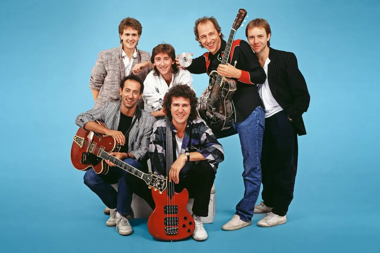 Członkowie Dire Straits z gitarami i basem, gotowi do rock'n'rolla.