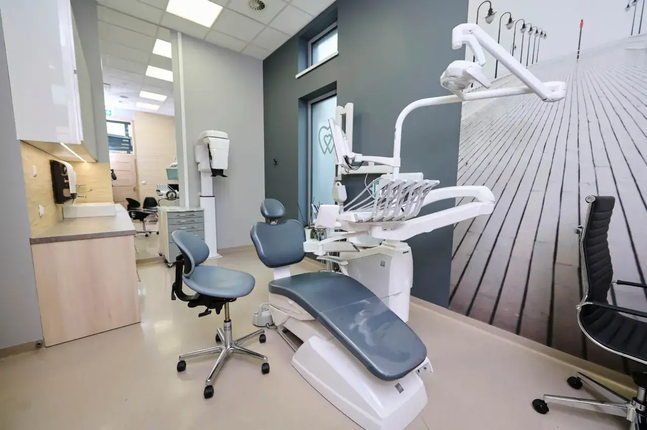 Nowoczesny gabinet stomatologiczny z fotelem dentystycznym i wyposażeniem.