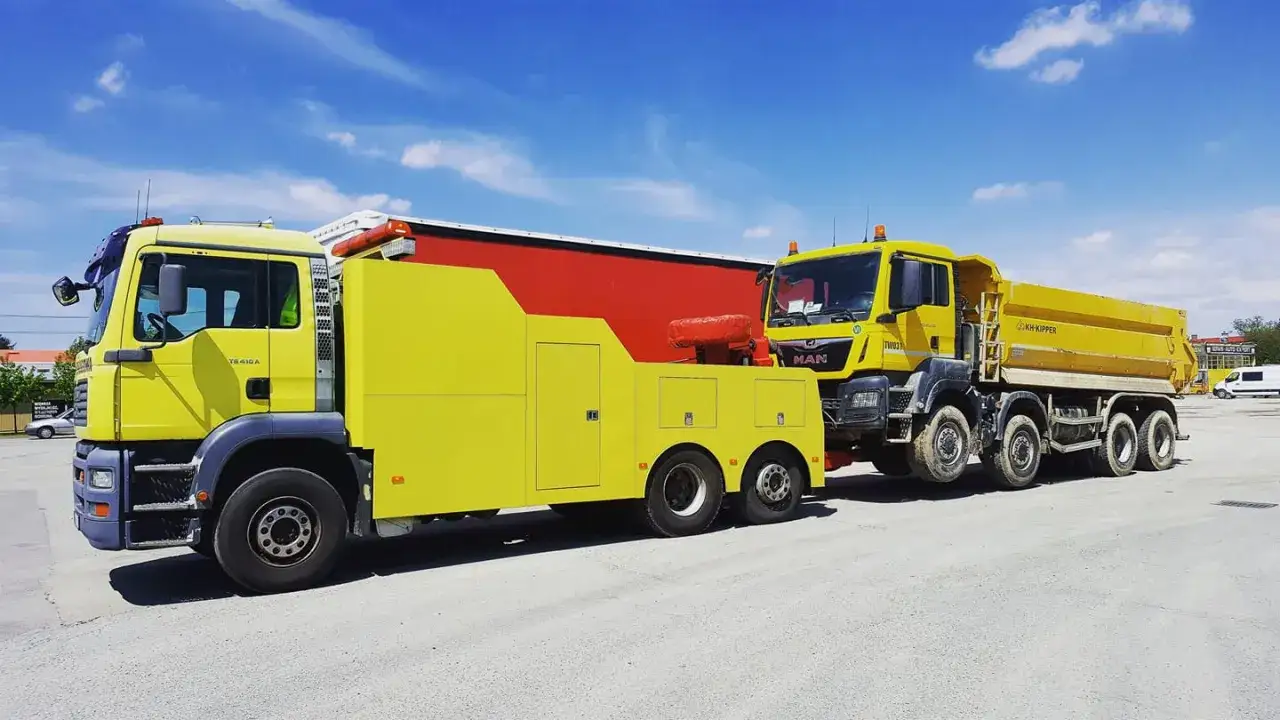 Ż&oacute;łty pojazd pomocy drogowej holuje ż&oacute;łtą wywrotkę. Gotowi na każde wyzwanie, zapewniają niezawodną truck assistance.