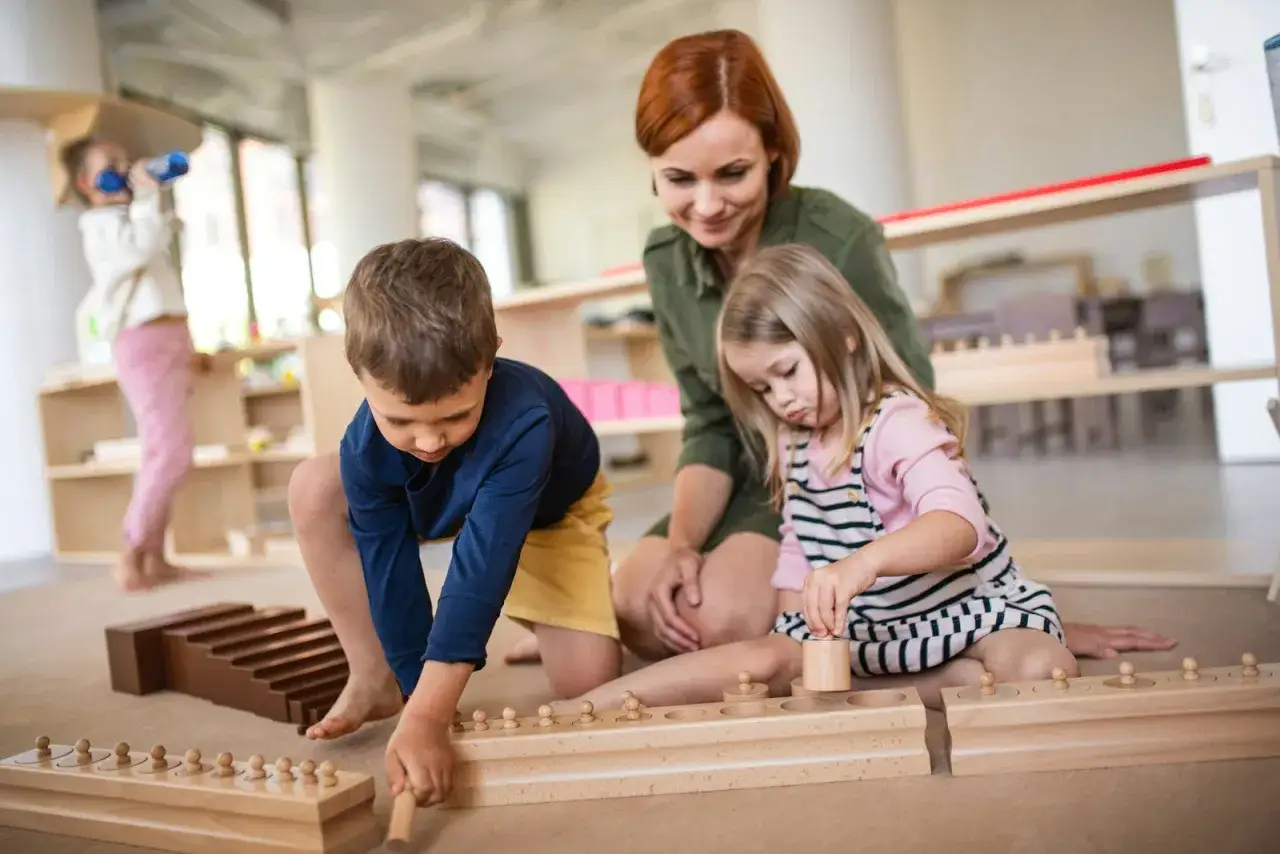 A teacher guides children in a mindful Montessori classroom, engaging with wooden learning toys.