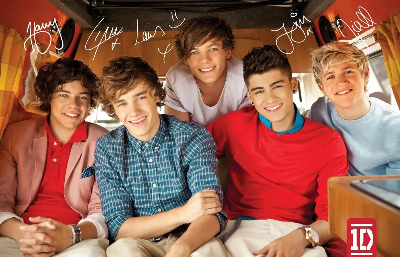 Uśmiechnięci członkowie One Direction: Harry, Liam, Louis, Zayn i Niall, siedzą razem, tworząc radosną atmosferę.