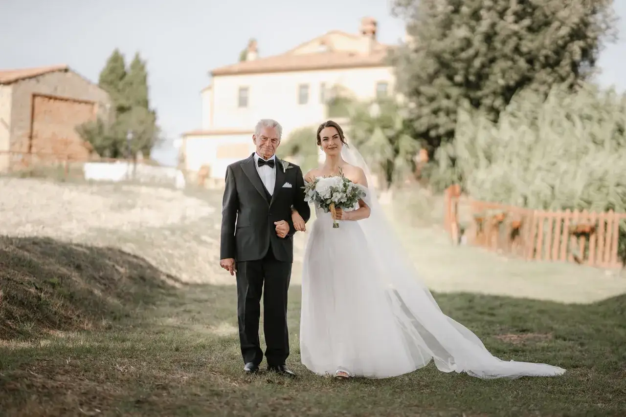 Il padre della sposa, con un elegante abito nero e papillon, accompagna la figlia all'altare.