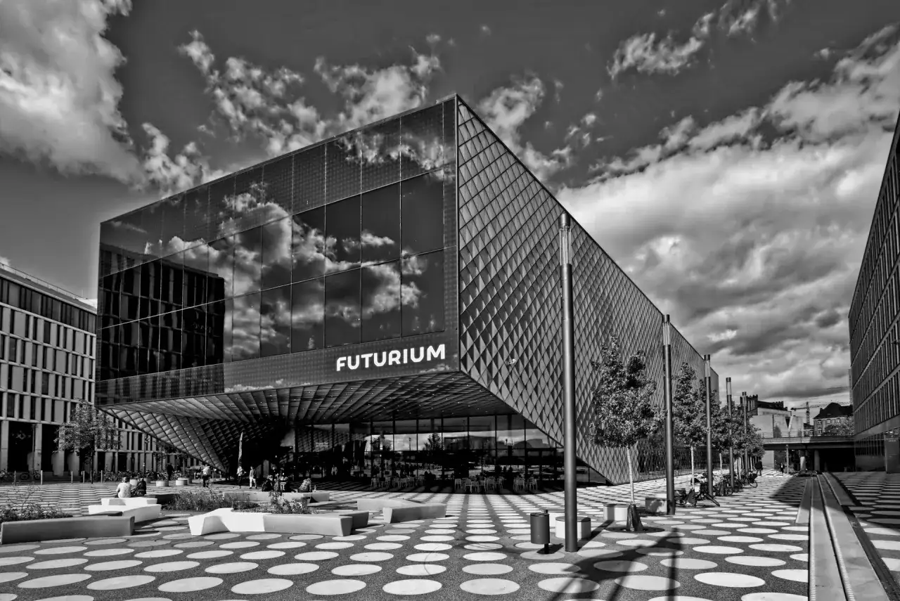 Futurium, muzeum sztuki nowoczesnej w Berlinie, z futurystyczną fasadą odbijającą chmury.