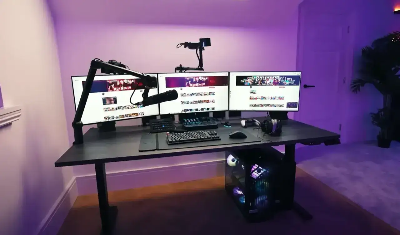 Ein Gaming-Setup mit drei Monitoren, Mikrofon und RGB-beleuchtetem PC. Perfekt, um viele Twitch Follower zu bekommen.