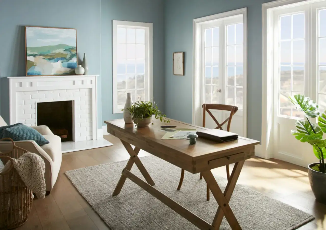 Bureau en bois avec une plante et des papiers, invitant à la concentration. La couleur bleue apaisante des murs crée une ambiance sereine.