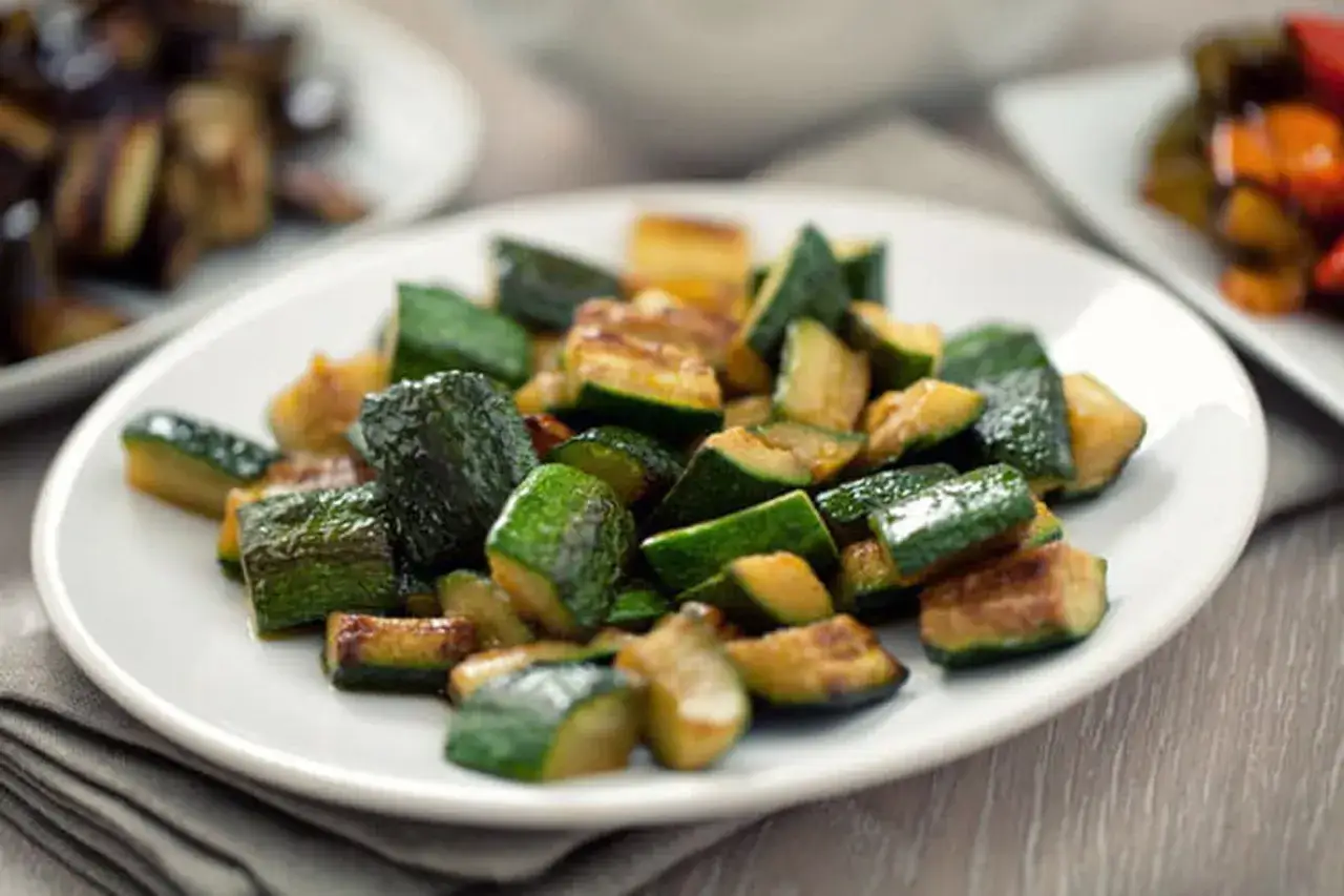 Délicieuse recette courgette coupée en dés, poêlée et servie sur une assiette blanche. Un plat simple et savoureux.