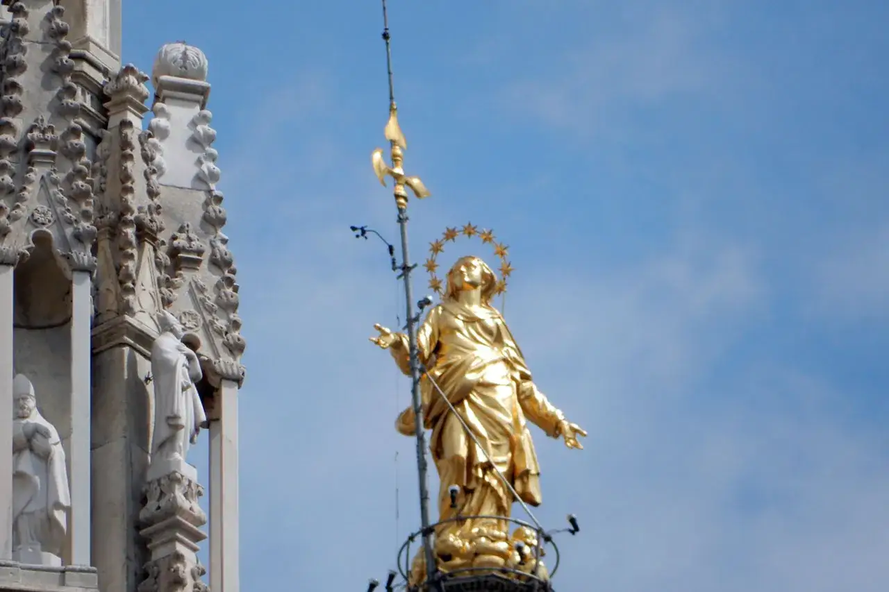 Złota Madonnina na szczycie katedry Duomo w Mediolanie, otoczona gwiazdami, góruje nad miastem.