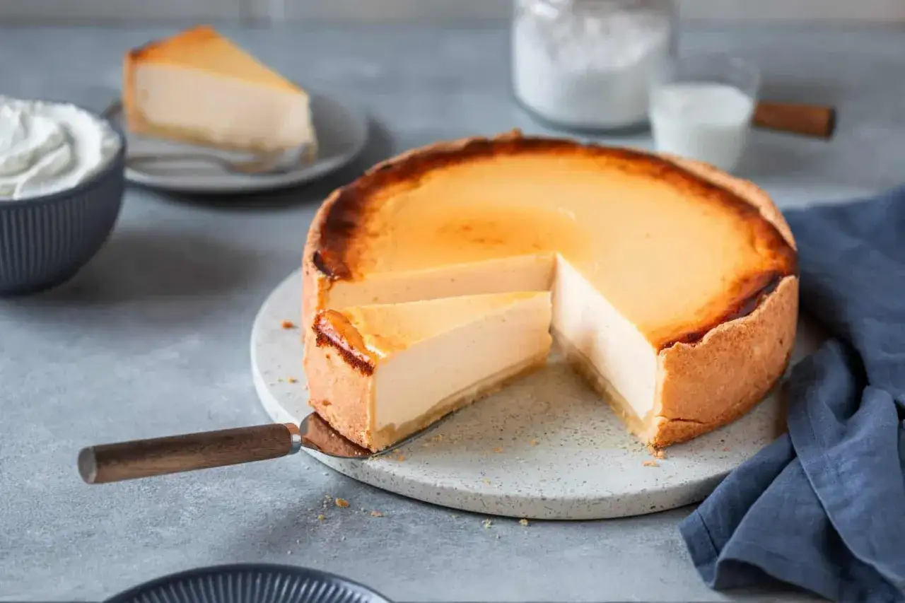 Ein k&ouml;stlicher K&auml;sekuchen, perfekt f&uuml;r ein einfaches cheesecake rezept. Ein St&uuml;ck wird gerade herausgeschnitten.
