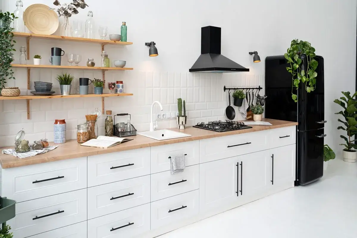 Cocina moderna y luminosa con muebles blancos y encimera de madera. Campana negra, nevera retro y estanter&iacute;as con detalles decorativos. &iexcl;Ideal para renovar cocina sin obras!