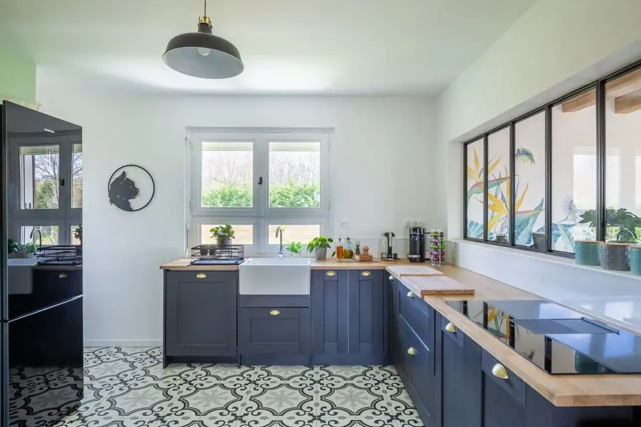 Une cuisine moderne avec un sol de cuisine tendance aux motifs g&eacute;om&eacute;triques, des armoires bleu marine et un &eacute;vier blanc.