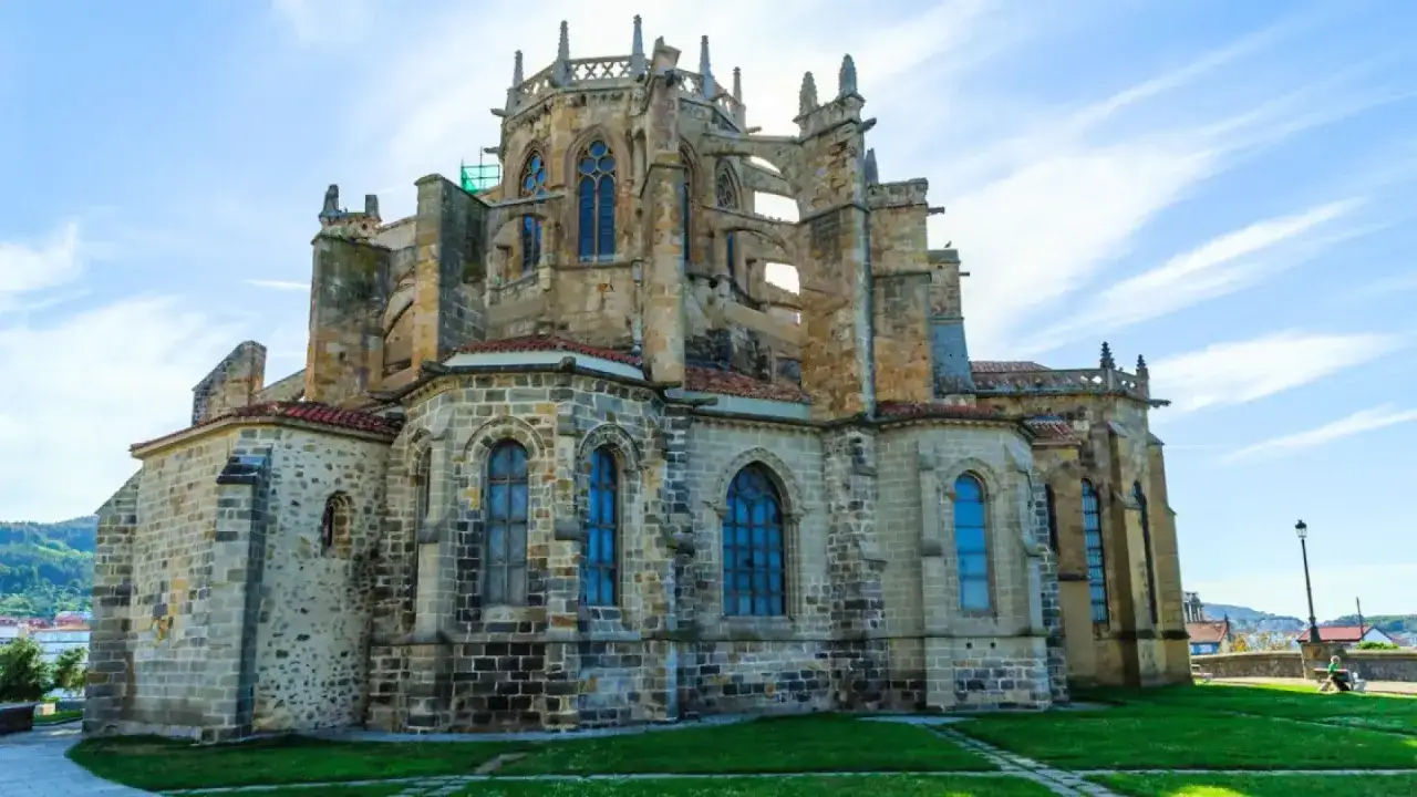 Impresionante iglesia gótica, un lugar clave que ver en Castro Urdiales. Sus arcos y vidrieras azules destacan bajo el cielo despejado.