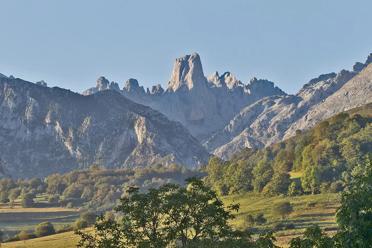 Majestatyczny **Naranjo de Bulnes** góruje nad jesiennym krajobrazem z zielonymi dolinami i skalistymi szczytami.