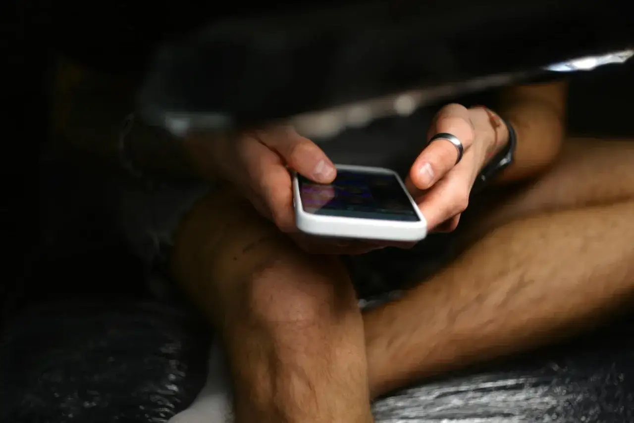 Ręce trzymające smartfon, przeglądające zdjęcia. Czy to FOMO co to? Strach przed przegapieniem czegoś ważnego w wirtualnym świecie.