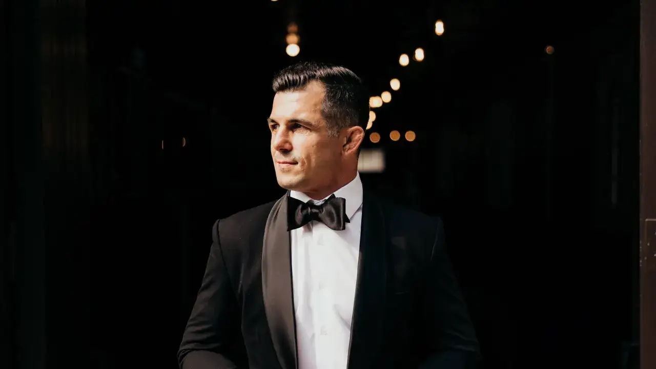A man in a tuxedo with a black bow tie, looking off to the side. He's dressed for a black tie event, so the question 