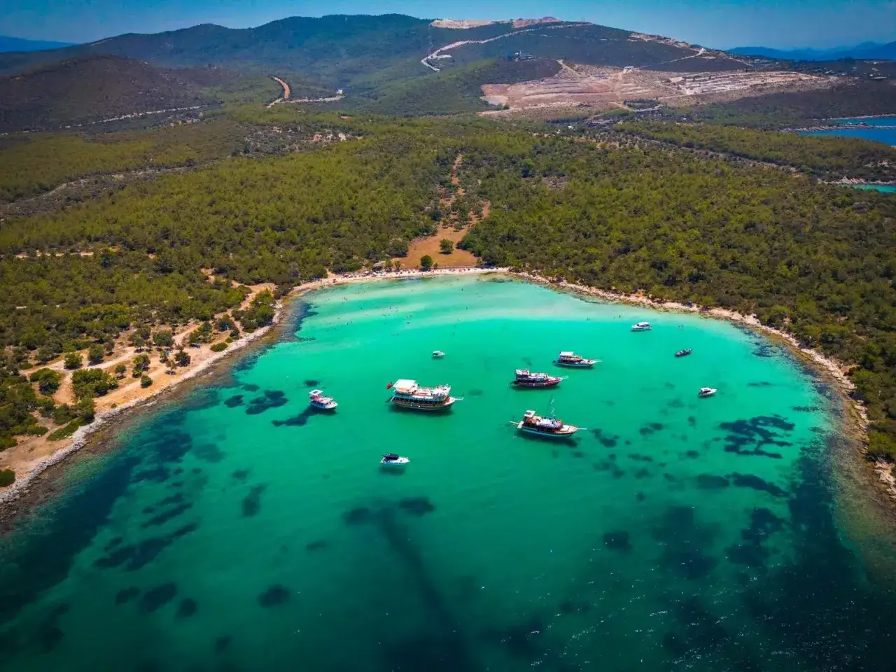 Albania najpiękniejsze plaże: turkusowa woda, zielone wzg&oacute;rza i łodzie cumujące przy brzegu. Raj dla miłośnik&oacute;w słońca i morza.