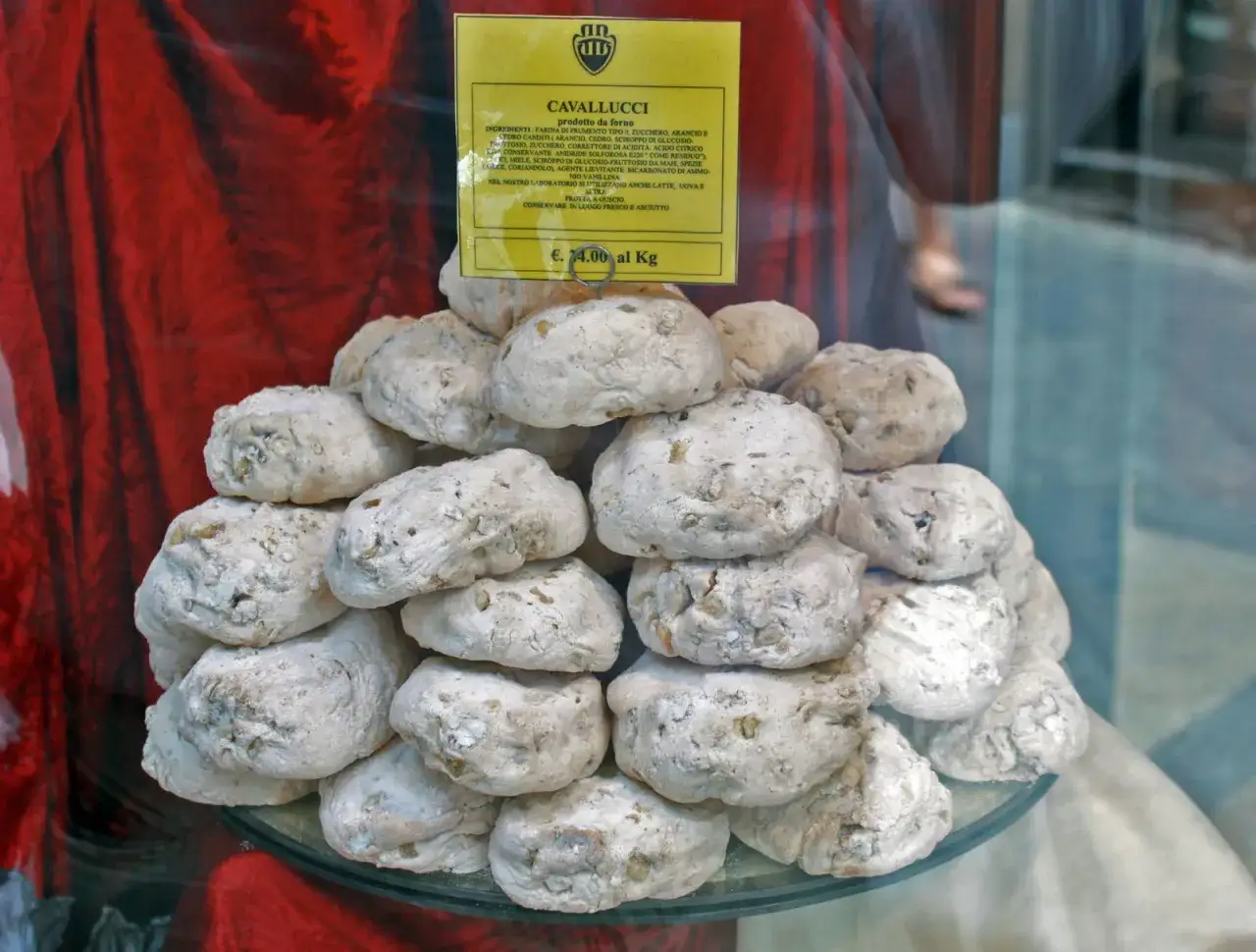 Dolce senese: cavallucci, biscotti rustici con noci e agrumi, impilati su un piatto di vetro.