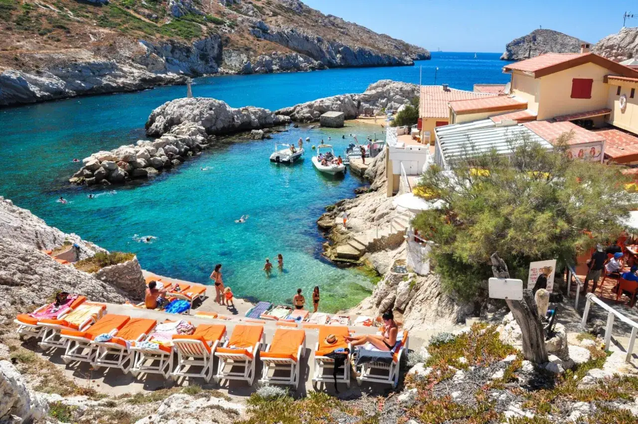 La plus belle plage de Marseille, une crique aux eaux turquoise, baigneurs, bateaux et transats sous le soleil.