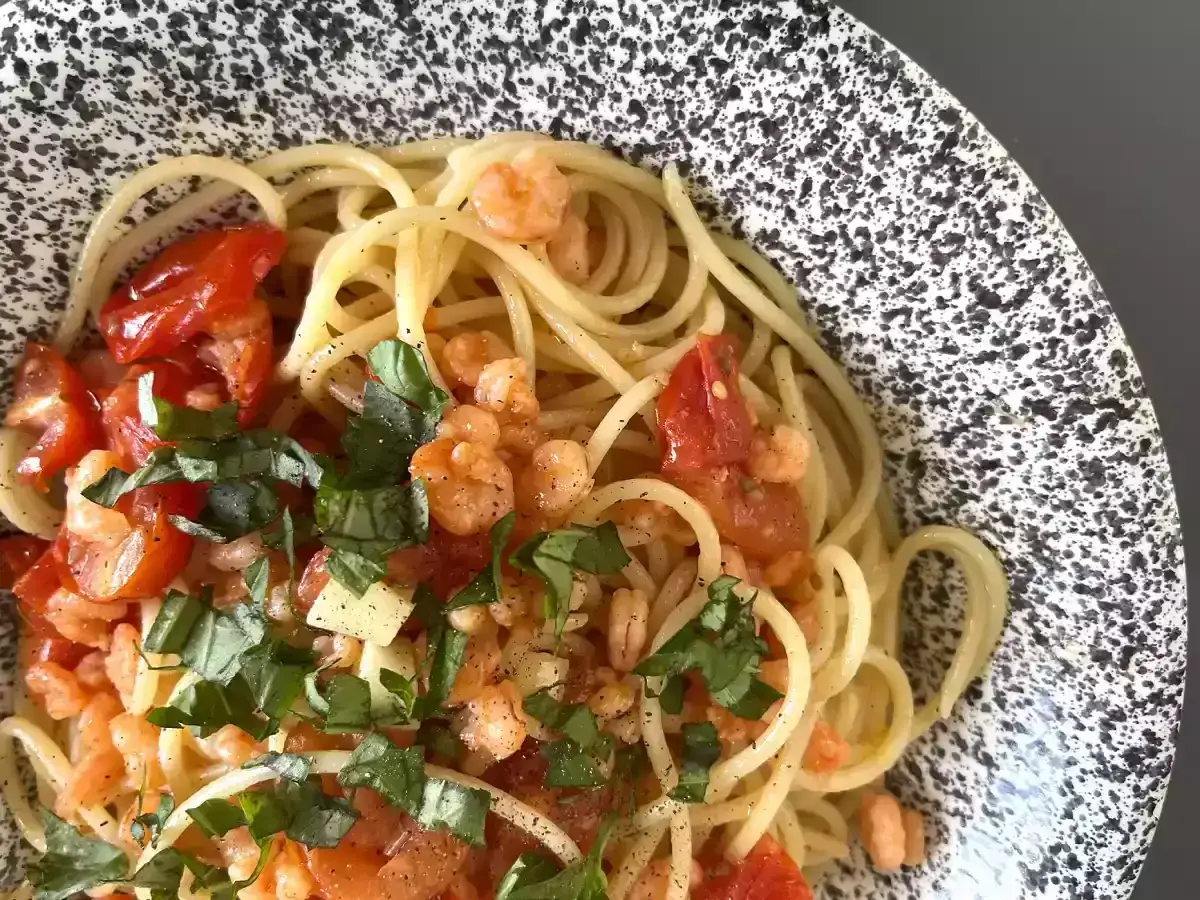 Spaghetti con gamberetti, pomodorini e basilico fresco, un piatto colorato e profumato.