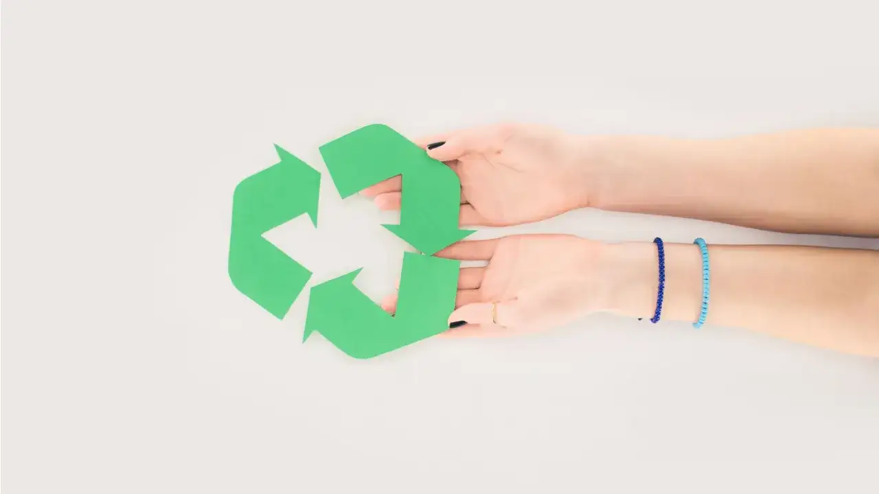 Dwie dłonie trzymają zielony symbol recyklingu. Pomyśl, co zrobić ze starym materacem, by go odzyskać.