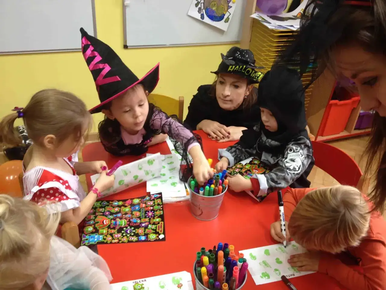 Dzieci, w tym 7 latek, tworzą halloweenowe ozdoby. Wesoła zabawa z kolorowymi pisakami i naklejkami.