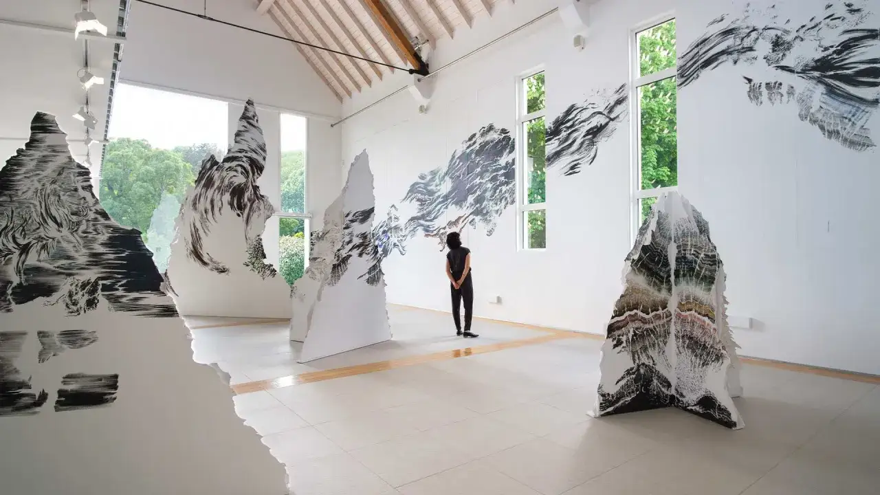 Installation d'art d'Abdelkader Benchamma : formes d&eacute;coup&eacute;es aux motifs abstraits et organiques, une personne observe l'&oelig;uvre.