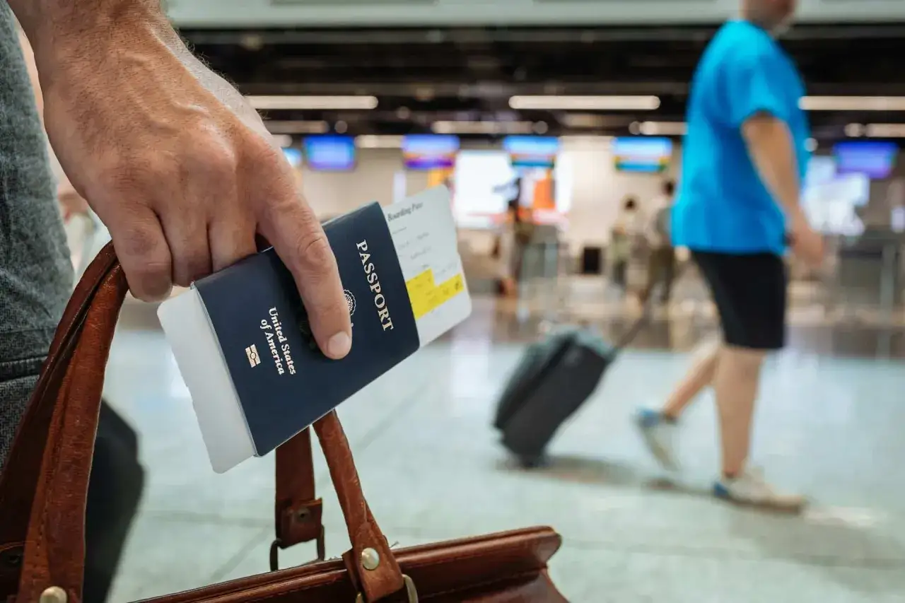 Ręka trzyma paszport USA i kartę pokładową. Czy do Anglii potrzebny jest paszport? Tak, do podróży do Anglii potrzebny jest paszport.