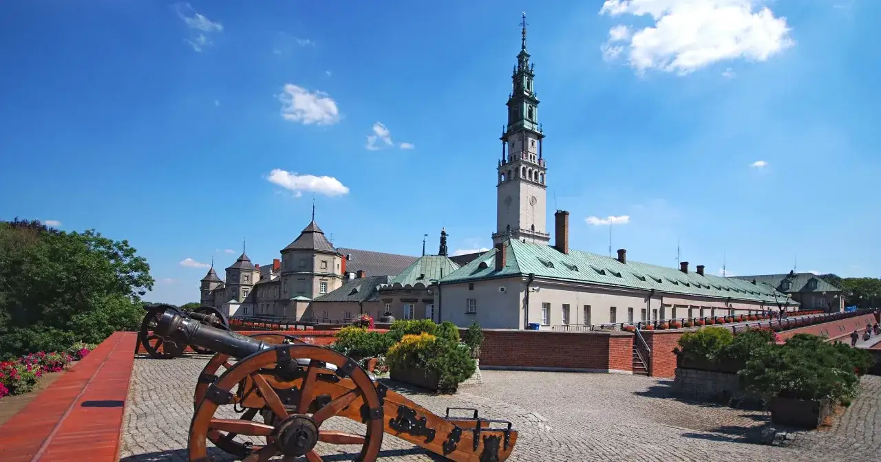 Jasne niebo nad Jasną G&oacute;rą. Dwa zabytkowe działa na pierwszym planie, a w tle klasztor. Idealne częstochowa atrakcje na weekend.
