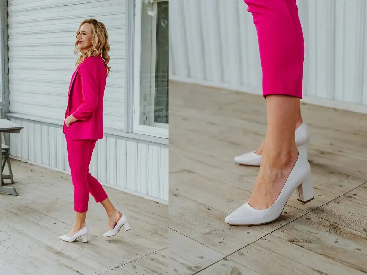 Elegancka kobieta w fuksjowym garniturze i białych czółenkach na słupku. Idealne buty do jasnego garnituru, które dodają klasy.