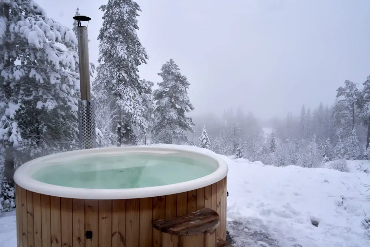 Drewniane jacuzzi w śnieżnym lesie, gotowe do zimowych kąpieli. Warto wiedzieć, jak złożyć jacuzzi na zimę, by cieszyć się nim dłużej.