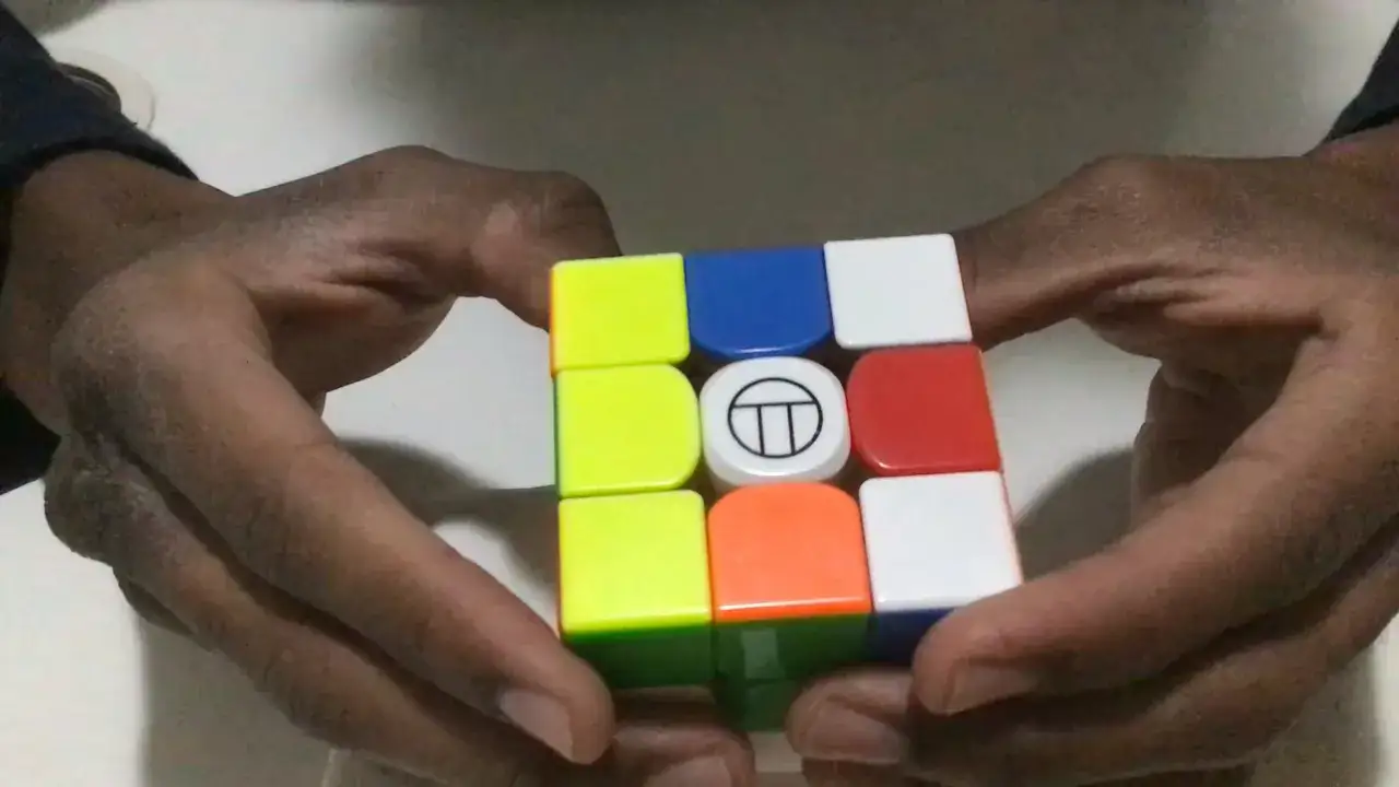 H&auml;nder h&aring;ller en rubiks speed cube med f&auml;rgglada sidor.