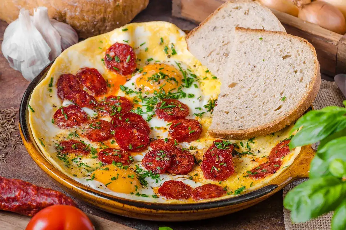 Jajecznica z chorizo, posypana szczypiorkiem, podana z chlebem. Pyszne śniadanie, kt&oacute;re rozwieje wątpliwości: chorizo co to jest - to dodatek, kt&oacute;ry wzbogaci każde danie!
